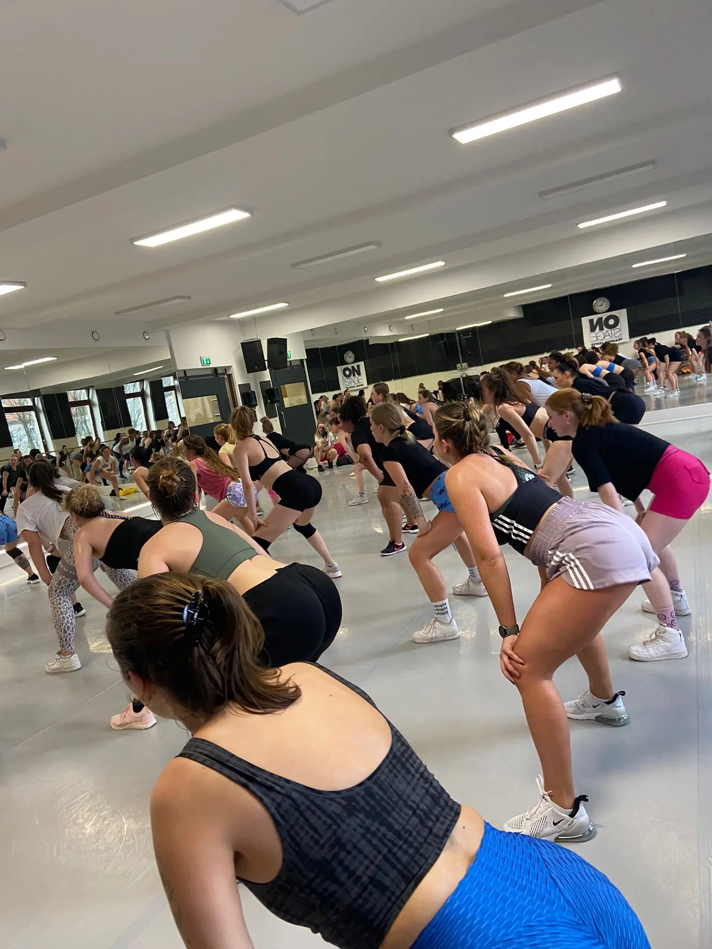 Dancers practising twerk foundations together in a beginner workshop.